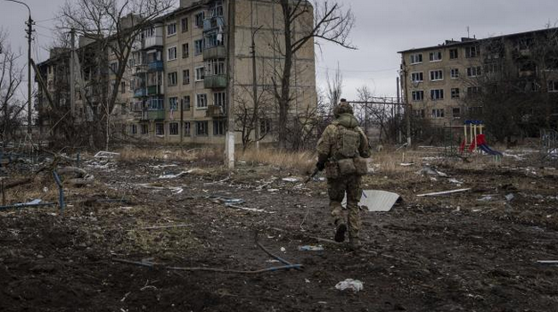 Украински военнослужещ бяга, за да заеме позиция в жилищна сграда в град Вухледар, Украйна.